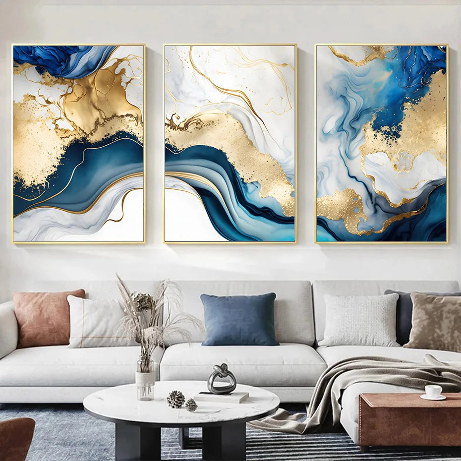 3 modern art canvases hanging on the wall above a sofa. They are blue, gold and white.